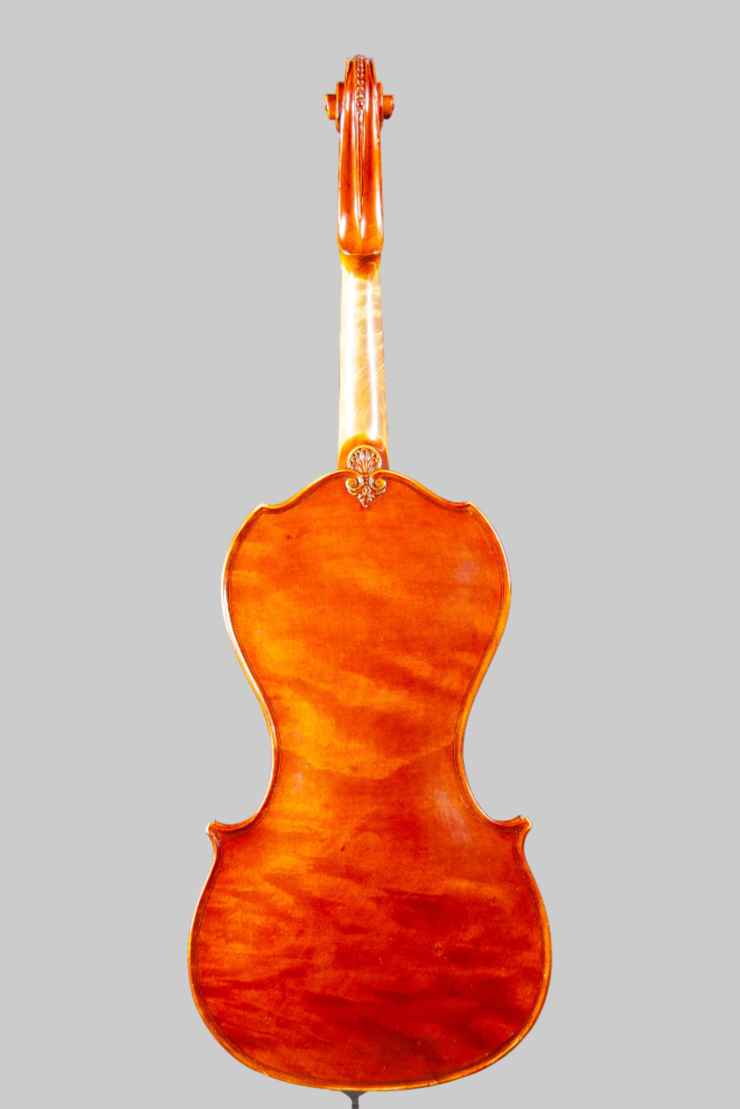 Back view of a violin on a stand against a dark background