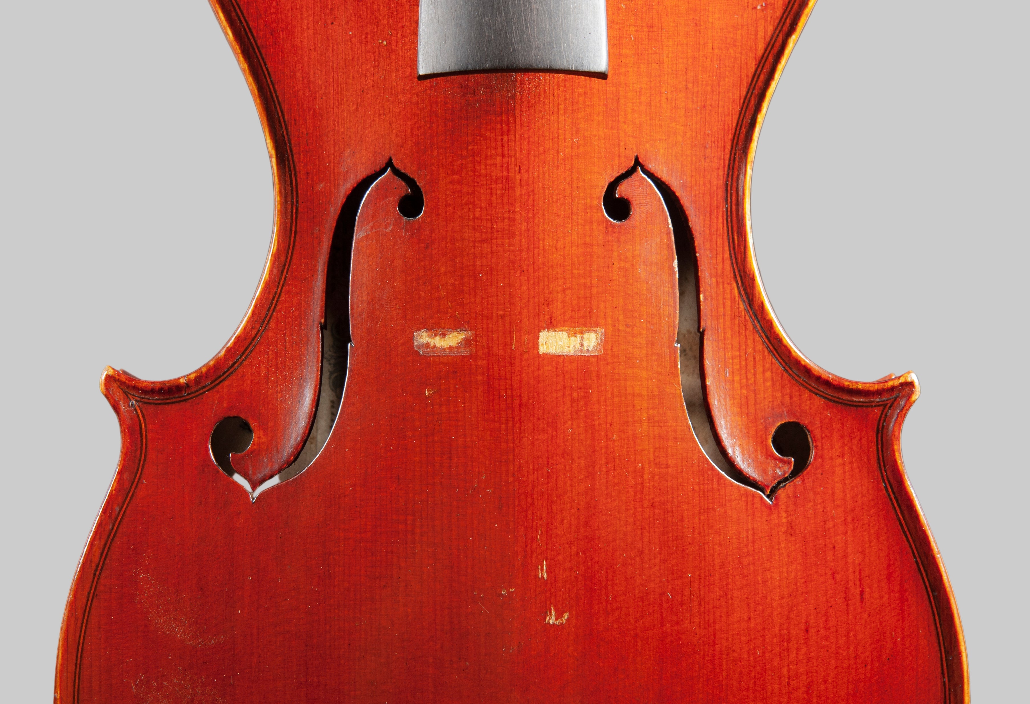 Close-up of a violin's back with a blurred gray background